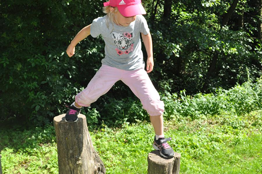 Girl standing on two tree trunks