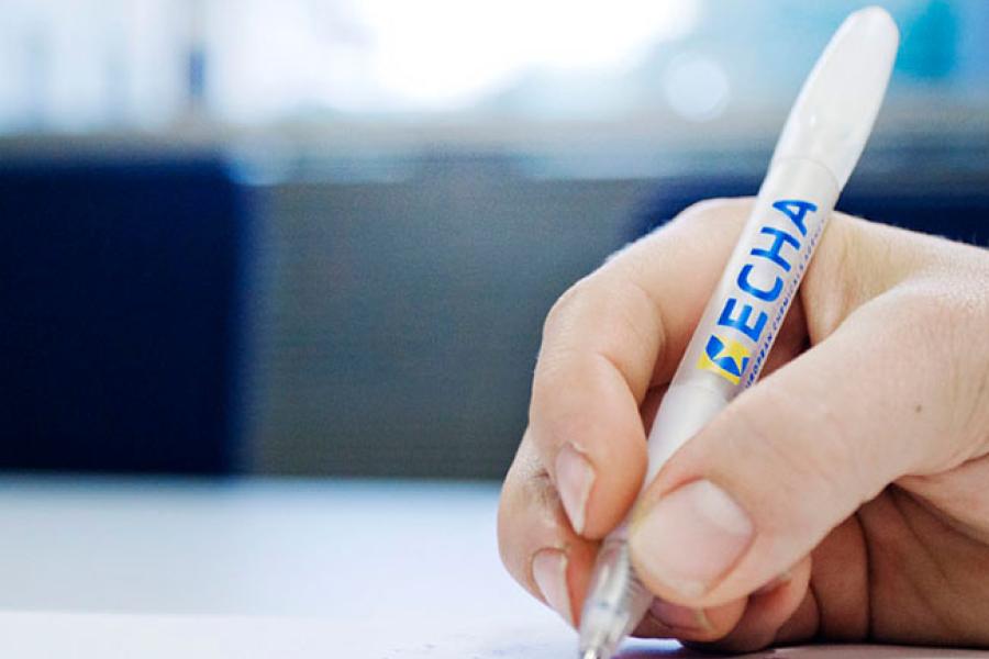 Person writing with a pencil with the ECHA logo on it